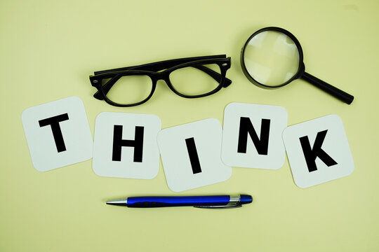 THINK alphabet letters with magnifying glass, eye glasses and pen on yellow background