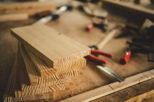 Stack of Wooden Boards and Carpentry Tools on Workshop Workbench