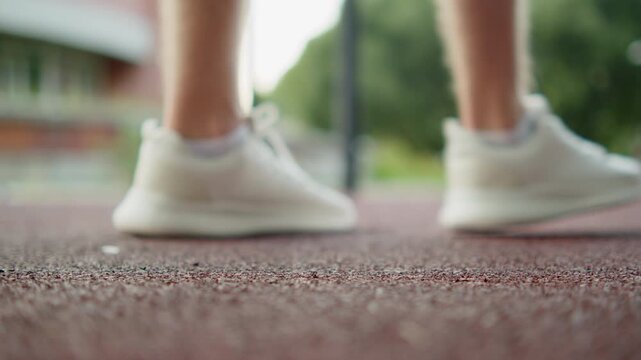 Putting on white training shoes. Close up shot of a person putting on a white running shoes on an outdoor sports ground. Man preparing for a workout session on an outdoor playground.