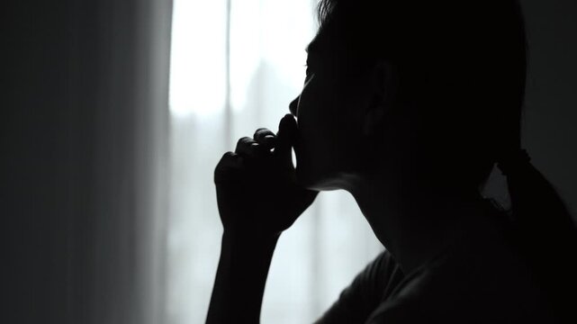 Woman with depression crying in a dark room, expressing sadness and emotional distress from family problems, relationship issues, stress, abuse, and loneliness.