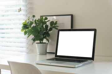 Fototapeta premium Minimal home office workspace with laptop mockup, headphones, coffee cup, notebooks, pencils, and small plant on a clean white desk.
