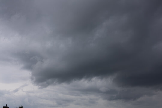 Dramatic Dark Storm Clouds Gathering Before Heavy Summer Rain. Dramatic formation of dark gray storm clouds filling the sky before an approaching summer rainstorm. The layered cloud formations