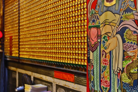 Golden blessing lamps and colorful door god painting in Taiwanese temple.