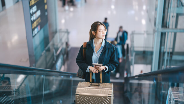 Young asian woman tourist passenger to transit wear blue dress with passport and travel luggage at international airport terminal