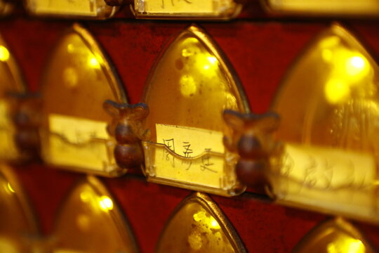 Close up of lit golden prayer lamps in a Taiwanese temple.