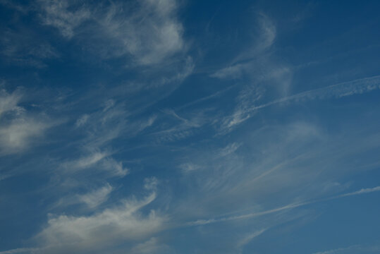 Clear blue sky with delicate cirrus clouds and visible airplane trails crossing the atmosphere, creating a peaceful natural background with subtle signs of air travel.
