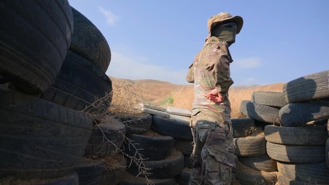 Military figure positioned among tire walls in desert environment