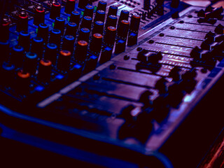 Fototapeta premium Moody Purple Lit Sound Mixer Console Faders and Knobs Close Up in Dark Ambiance