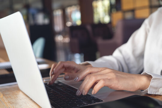 Close up, business woman hand typing on laptop computer, working remotely in coffee shop, digital nomad, modern business lifestyle, online job concept
