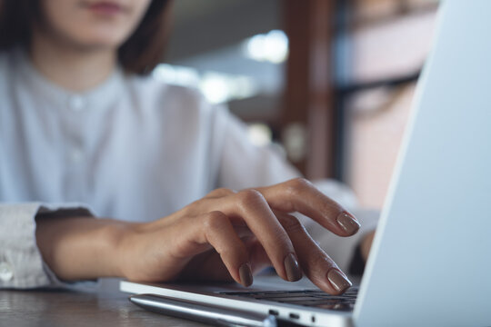 Close up, business woman hands typing on laptop computer, working remotely in cafe or modern office,  online business lifestyle concept