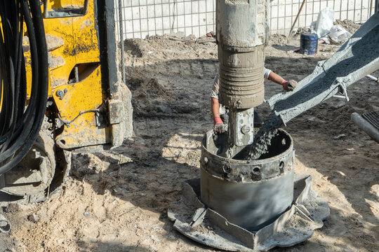 Construction worker operating heavy drilling machinery at foundation site, Industrial equipment pile driver and concrete foundation work 