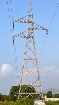 Towering electricity pylon carrying power lines against a clear blue sky