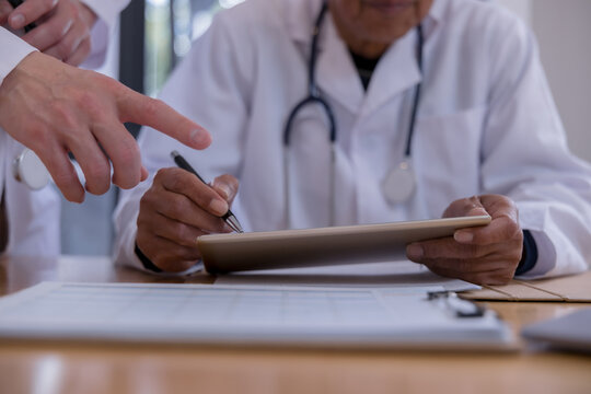 Medical team reviewing digital patient records with tablet and documents in a healthcare clinic. Doctors collaborating with health technology, electronic medical data, AI diagnostics modern clinical