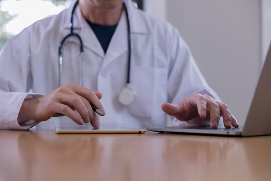 Doctor using a digital tablet to review patient records during a medical consultation in a healthcare clinic. Professional physician managing electronic health data diagnosis