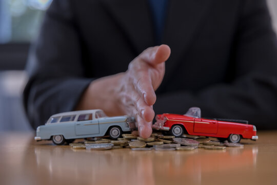 representing vehicle insurance separates toy cars with hand and coins on table risk management, accident prevention, transportation cost and safety concept.