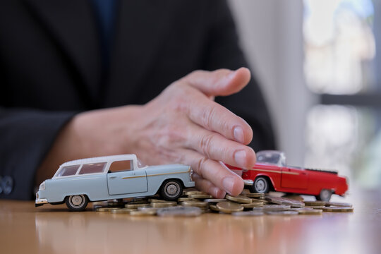 representing vehicle insurance separates toy cars with hand and coins on table risk management, accident prevention, transportation cost and safety concept.