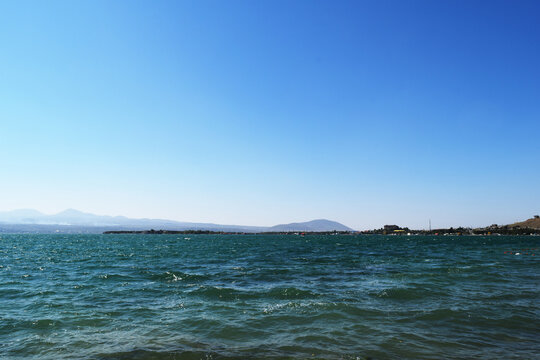 View of Lake Sevan in Armenia with rippling turquoise water under a clear blue sky, distant shoreline and hazy mountains, serene highland landscape, peaceful travel destination