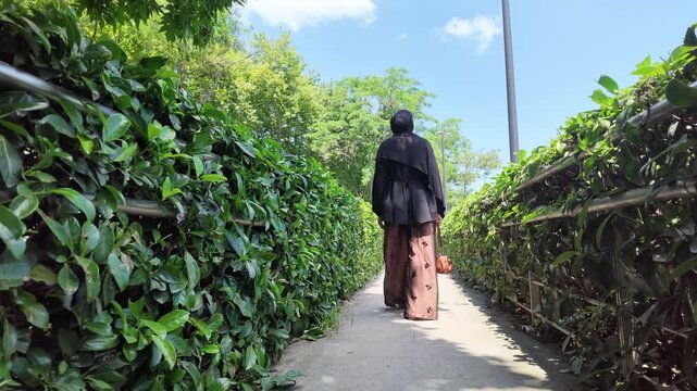 Walk through a path with bushes and trees in a park