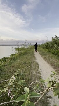 Slow Motion of Person Jogging on a Trail by the Water