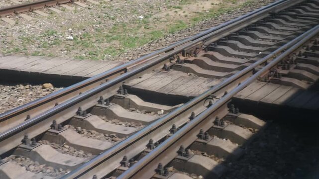 Close-up of moving railway tracks with gravel ballast and wooden sleepers from passing train. Motion blur creates dynamic travel atmosphere, fast transportation speed and journey concept 4k video