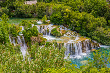 Krka National Park, Croatia, view of the Krka waterfall on a sunny day, featuring cascading water, lush greenery, wooden walkways, and a stunning natural landscape in bright Mediterranean light. © johnkruger1