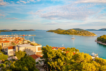 Naklejka premium View from Saint Michael’s Fortress in Šibenik, Croatia, at sunset, overlooking charming stone houses, the sparkling Adriatic Sea, and a breathtaking coastal panorama bathed in warm golden light.