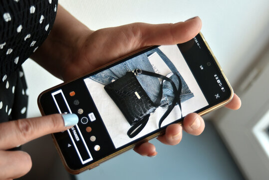 St- Amand Montrond - France - 5 August 2026 - Editorial detail of a woman's hands using a smartphone to add a stylish crocodile imitation handbag to a shopping cart on the Shein website.
