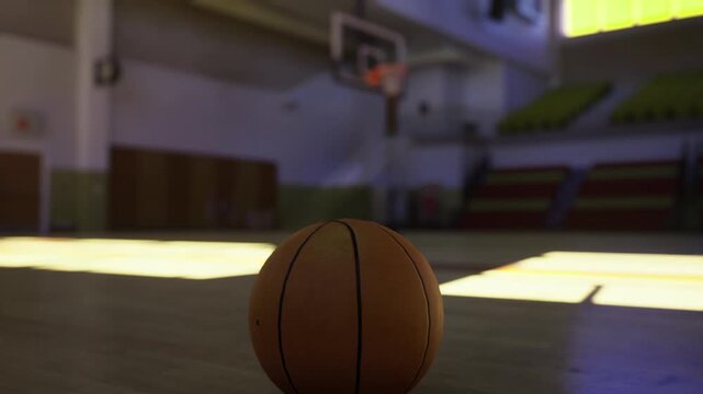 Silent basketball court with purple reflections and shadows. Radiant basketball surface with deep purple colors and expansive quietness surrounding it