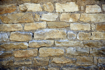 Fototapeta premium Close up view of a beige stone wall with beautiful masonry details, showing a natural architectural texture and traditional construction material. 