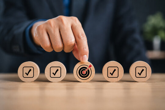 Business strategy and quality management concept with wooden block showing target icon and checklist, symbolizing quality control, workflow development, and goal-oriented process planning.