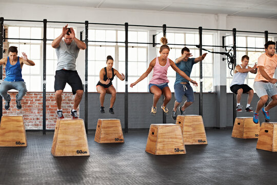 Gym, people and fitness group for jump on box as exercise, training and wellness in together. Men, women and resilience at facility for plyo workout, development and body health with equipment