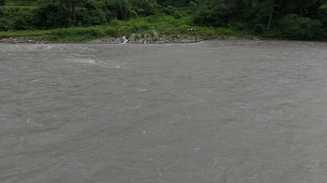 4K Drone View of Fast-Flowing Turbid River and Lush Green Riverbank