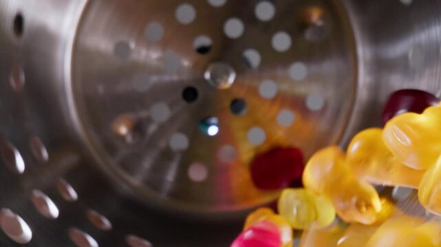 Colorful gummy bears marmalade sweets on industrial conveyor. Slow motion Food production with macro probe lens.