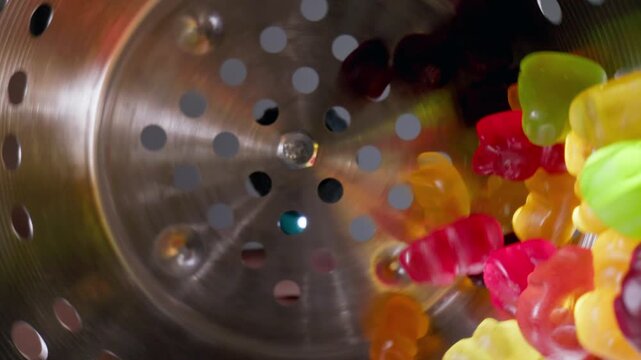 Slow motion Food production of colorful gummy bears marmalade sweets on an industrial conveyor, macro probe view.