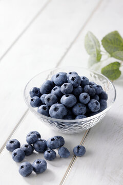 白い木目テーブルに置かれたボウルに入ったブルーベリー　Blueberries in a bowl on a white wooden table