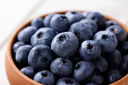 白い木目テーブルに置かれたボウルに入ったブルーベリー　Blueberries in a bowl on a white wooden table