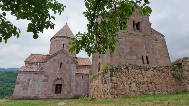 Stone Goshavank Monastery ruins with domes, framed by leaves