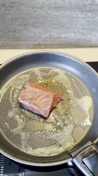 Raw seasoned meat steaks placed in oiled frying pan