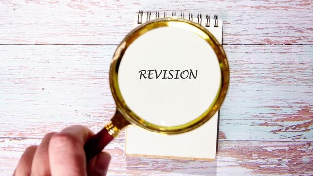 A hand uses a magnifying glass to reveal hidden text revisions on paper in a bright learning area