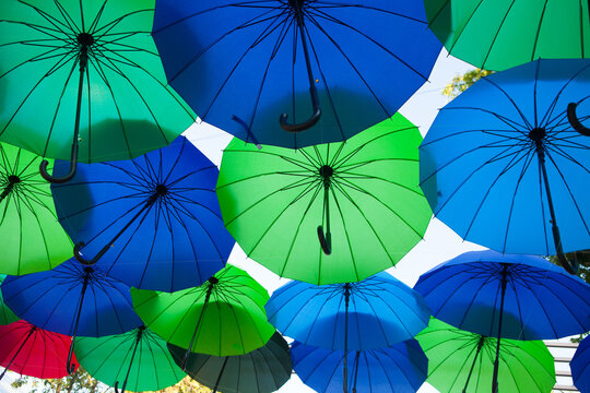 A bright canopy of blue and green umbrellas fills the outdoor view, vibrant decorative display, creative festival background.