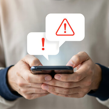Hands holding a smartphone displaying multiple urgent notification alerts and warning signs
