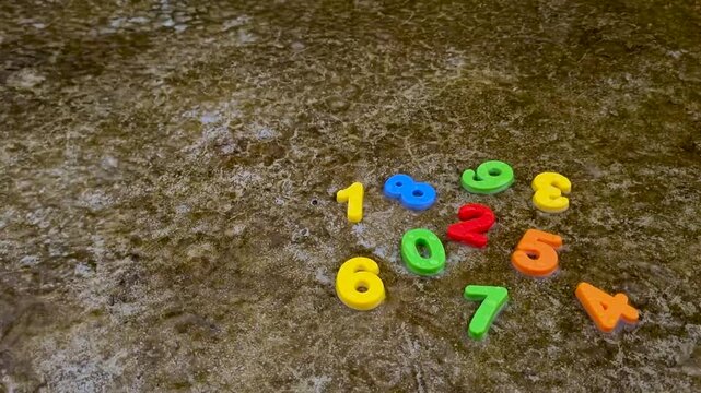 Colorful plastic numbers scattered on rough textured mossy stone ground moss math counting education