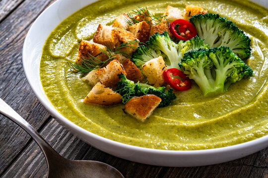 Garnished cream broccoli soup on wooden table
