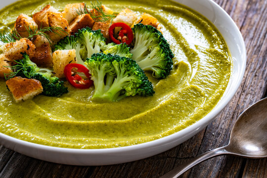 Garnished cream broccoli soup on wooden table
