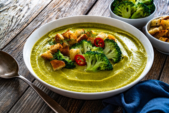 Garnished cream broccoli soup on wooden table
