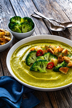 Garnished cream broccoli soup on wooden table
