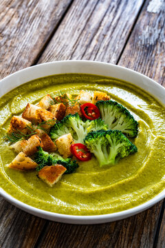 Garnished cream broccoli soup on wooden table
