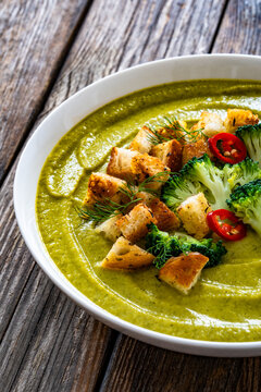 Garnished cream broccoli soup on wooden table
