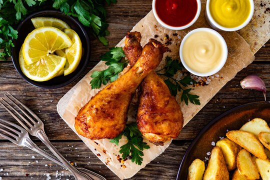 Air fryer chicken drumsticks with mayonnaise, ketchup and mustard on wooden table. Top view


