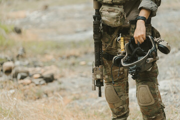 Fototapeta premium Outdoor military concept. Soldier standing in camouflage uniform with rifle and helmet feeling brave and confident during tactical military operation training
